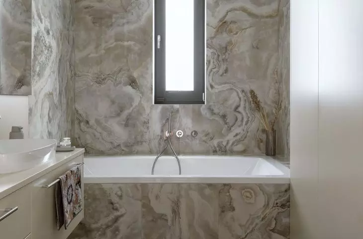 The alcove with the bathtub was tiled with tiles imitating onyx