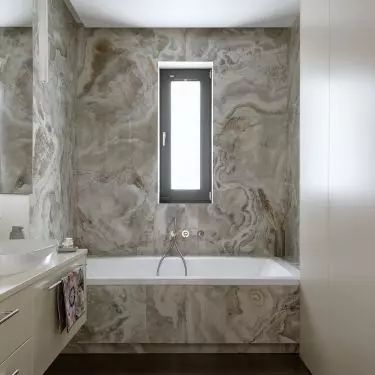 The alcove with the bathtub was tiled with tiles imitating onyx