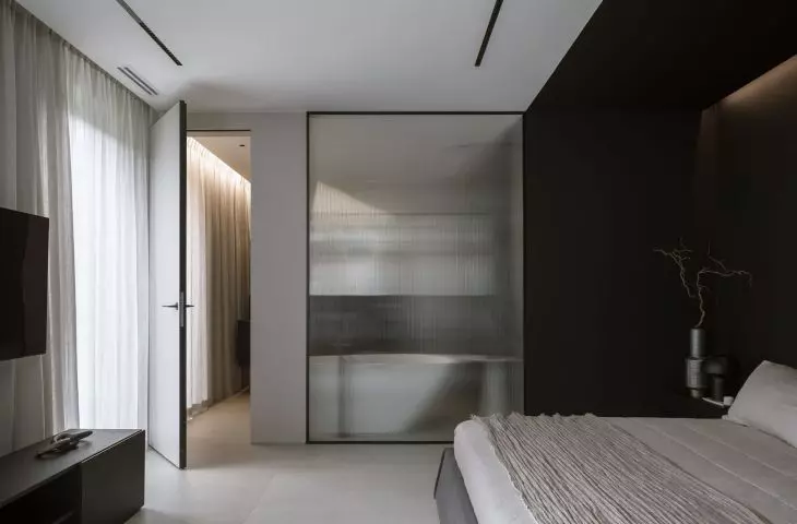 A sheet of fluted glass separates the bedroom from the bathroom