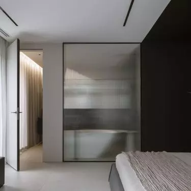 A sheet of fluted glass separates the bedroom from the bathroom