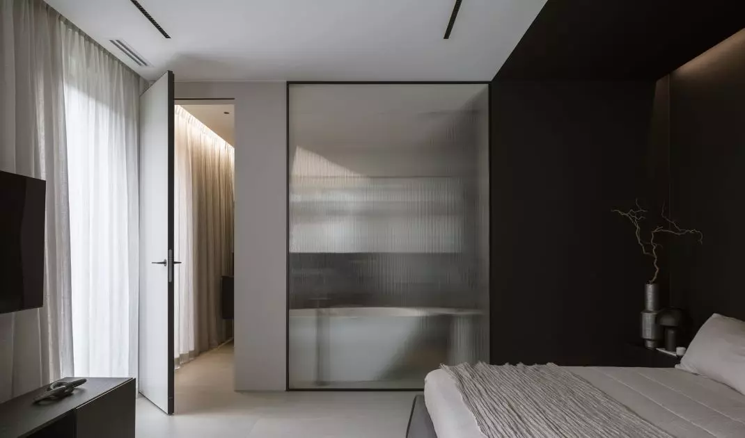 A sheet of fluted glass separates the bedroom from the bathroom