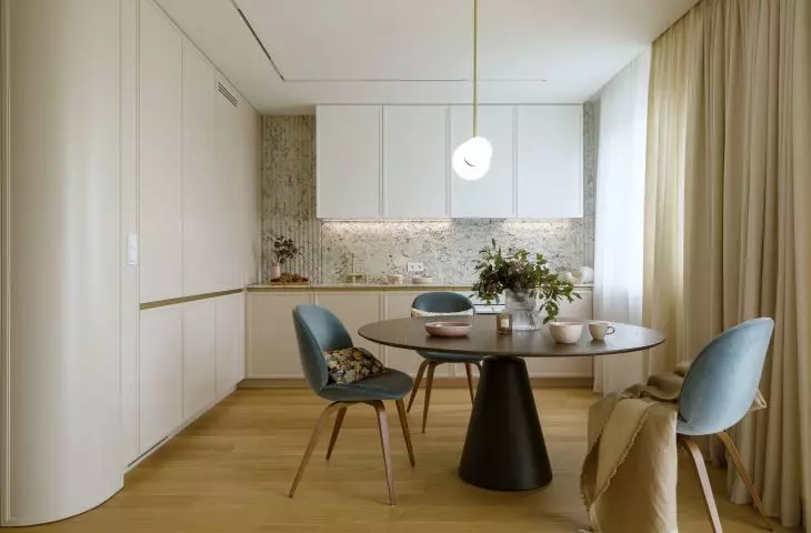 Black table and blue chairs break up the subdued arrangement