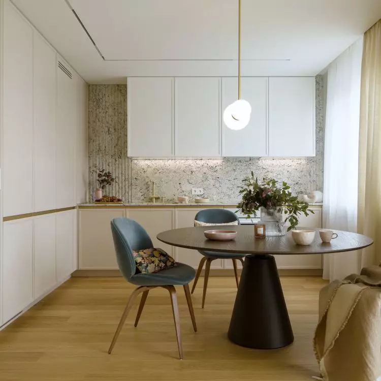 Black table and blue chairs break up the subdued arrangement