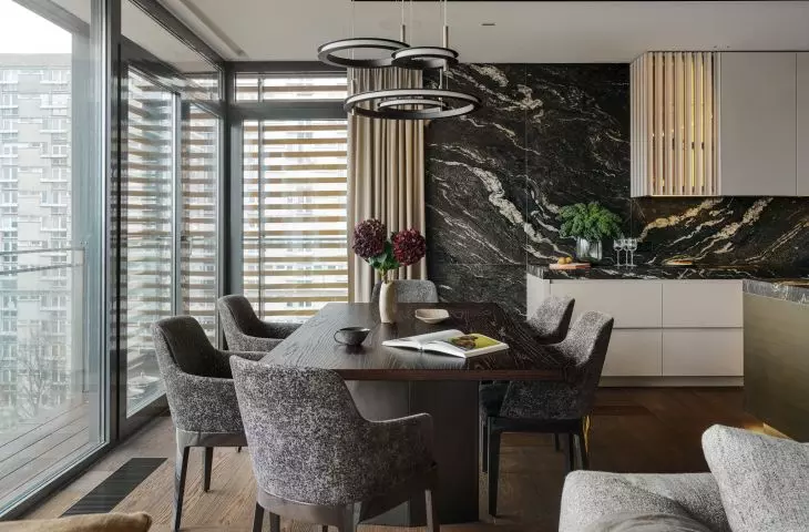 The grain of the table and the upholstery of the chairs refer to the stone used in the kitchen