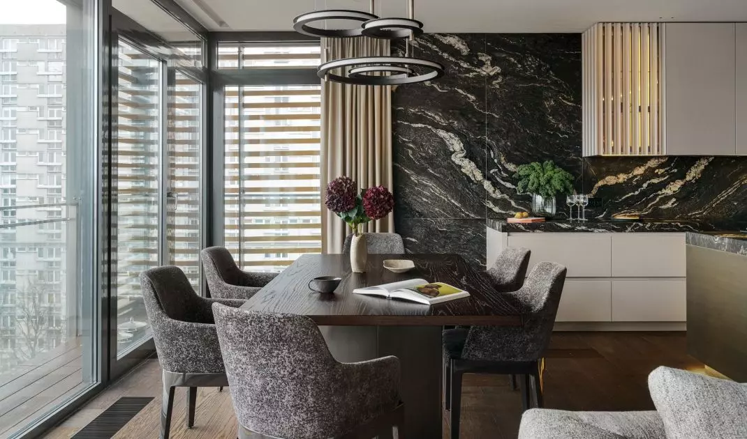The grain of the table and the upholstery of the chairs refer to the stone used in the kitchen