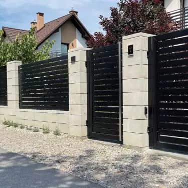 Ogrodzenie murowane z białych bloczków w kompozycji z czarnymi elementami z aluminium