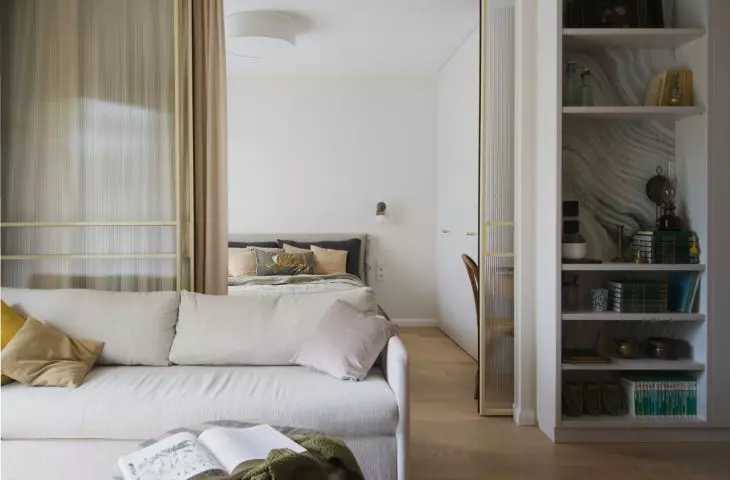 The bedroom is separated from the living room by a glass door
