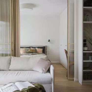 The bedroom is separated from the living room by a glass door