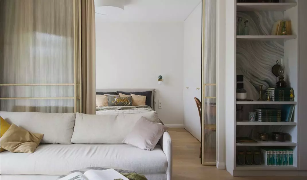 The bedroom is separated from the living room by a glass door