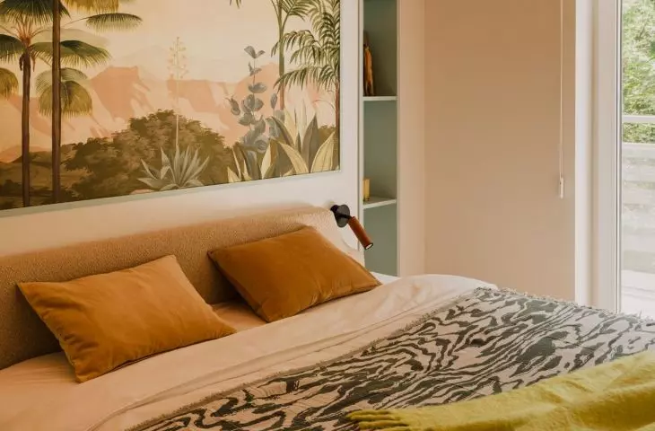 The wall behind the bed is decorated with painterly wallpaper