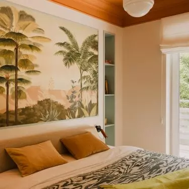 The wall behind the bed is decorated with painterly wallpaper