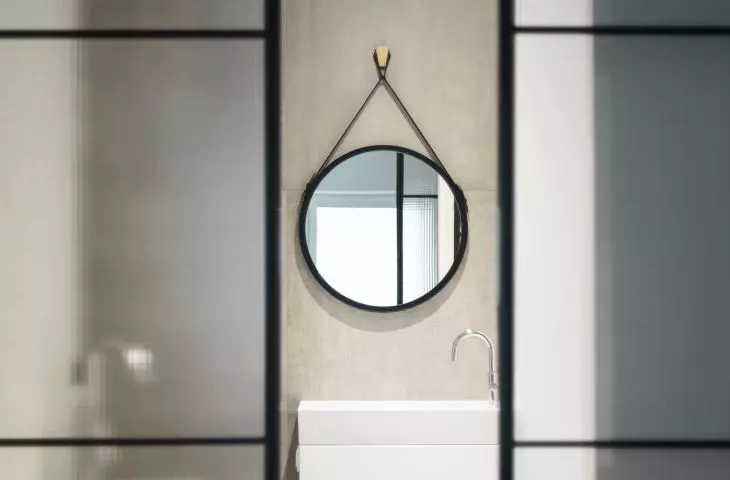 A glass door with a metal frame leads to the bathroom