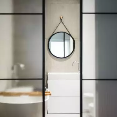 A glass door with a metal frame leads to the bathroom