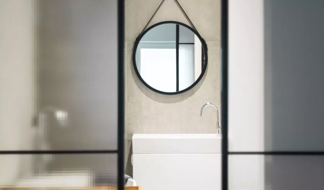A glass door with a metal frame leads to the bathroom