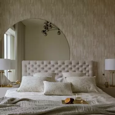 The wall behind the bed was decorated with wallpaper and a large semi-circular mirror
