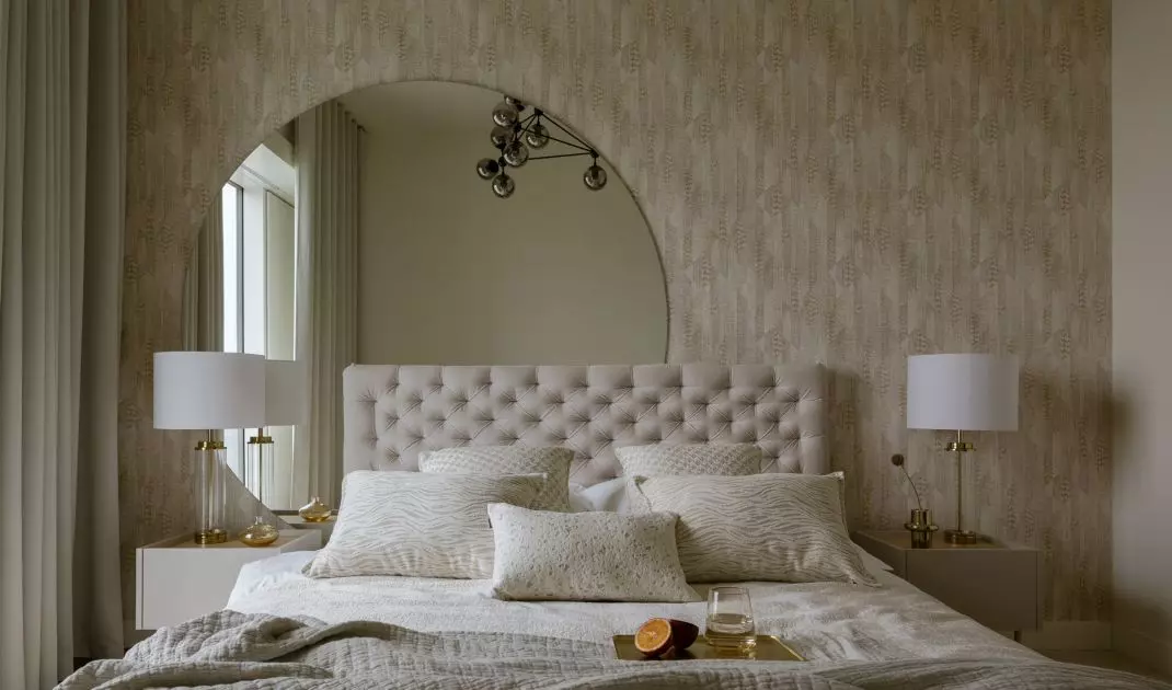 The wall behind the bed was decorated with wallpaper and a large semi-circular mirror