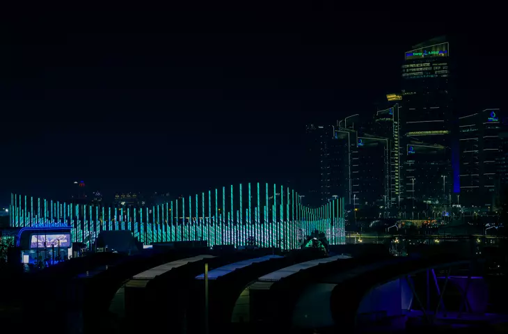 An exterior view of the building at night, with the Doha skyline in the background