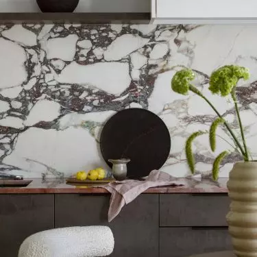 The wall above the countertop is covered with tiles imitating marble