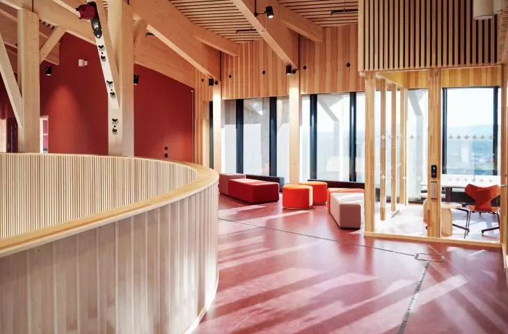 The interior of the building, with its walls in a warm red hue and natural wood, exudes a cozy and harmonious atmosphere