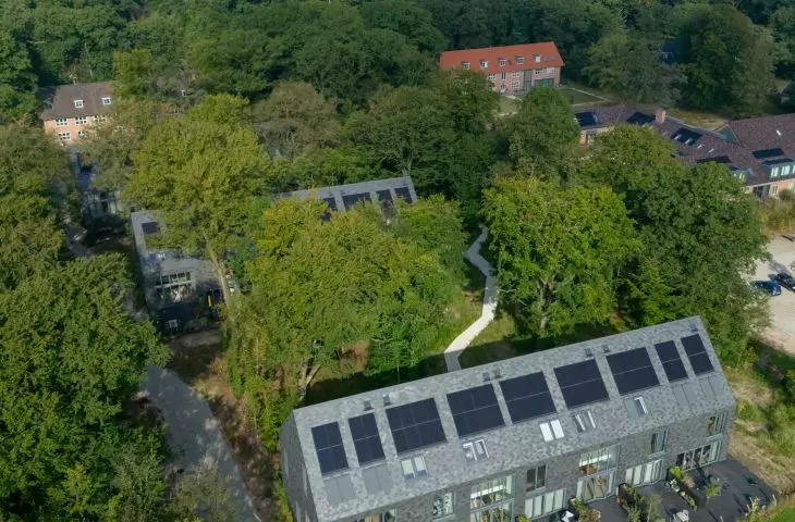 Widok z lotu ptaka na dom ukryty wśród zieleni z panelami słonecznymi na dachu