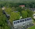 Aerial view of house hidden among greenery with solar panels on roof