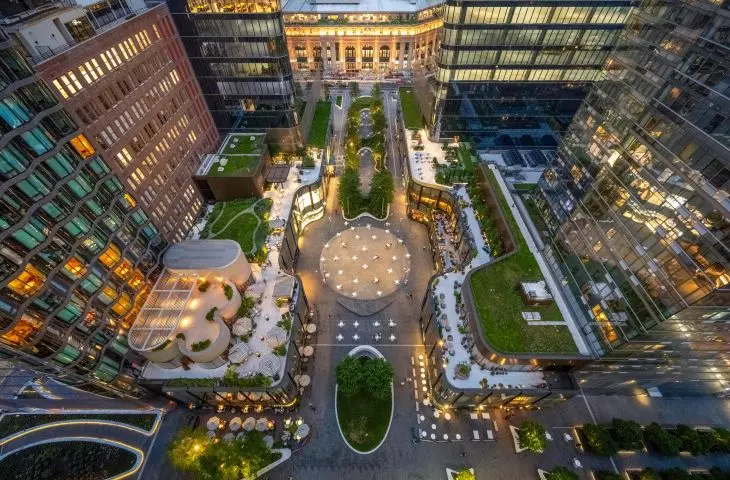 Aerial view of a modern courtyard with a central seating area, surrounded by multi-story buildings with green grass roofs