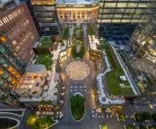 Aerial view of a modern courtyard with a central seating area, surrounded by multi-story buildings with green grass roofs