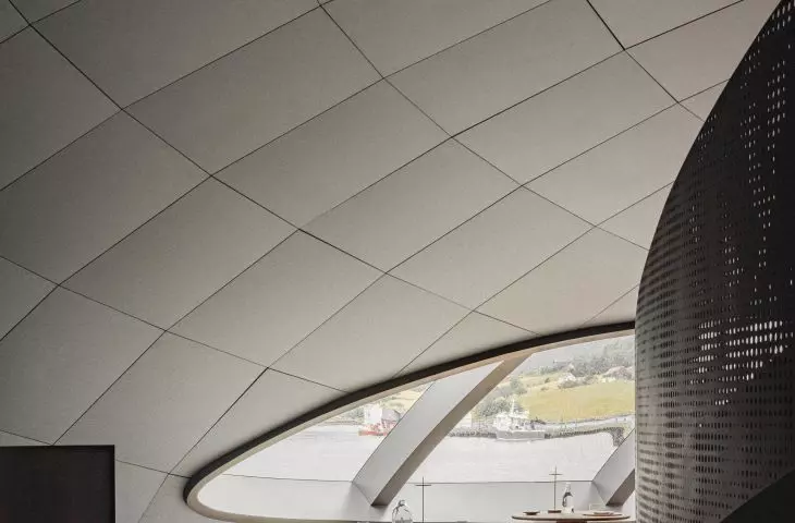 Modern space with curved ceiling, large oval window and sleek, minimalist dining furniture