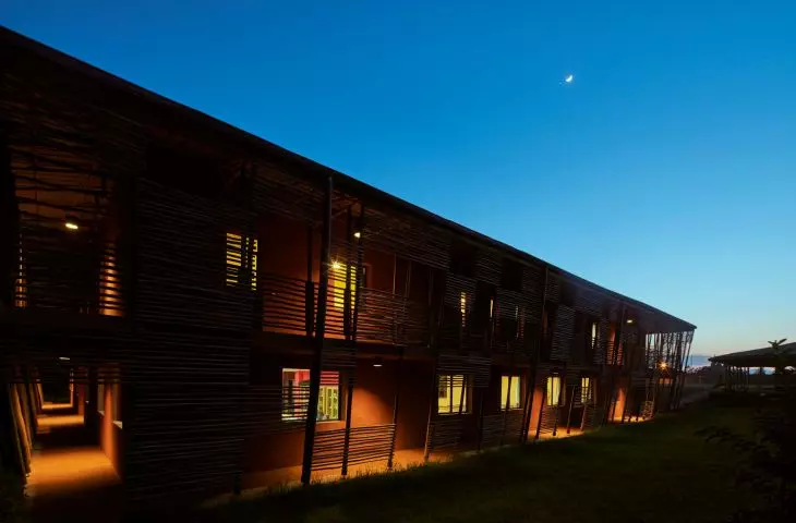 Side view of a modern wooden building at dusk with a crescent moon in the sky