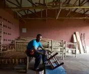 A man varnishing a wooden chair in a carpentry workshop