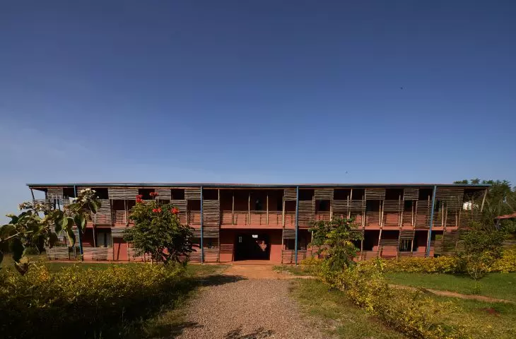 Dwupiętrowy budynek Busajo Campus od frontu, przylegający do ogrodu, w tle bezchmurne niebo