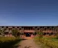 Busajo Campus two-story building in front, adjacent to the garden, cloudless sky in the background