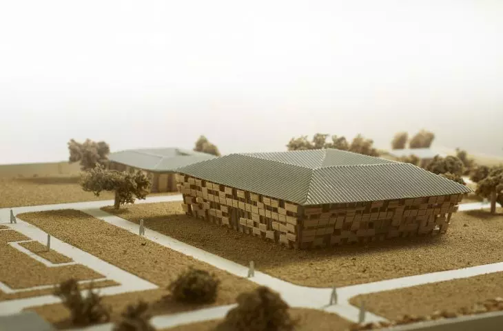 Model architektoniczny głównego budynku kampusu otoczony ścieżkami i miniaturowymi drzewami