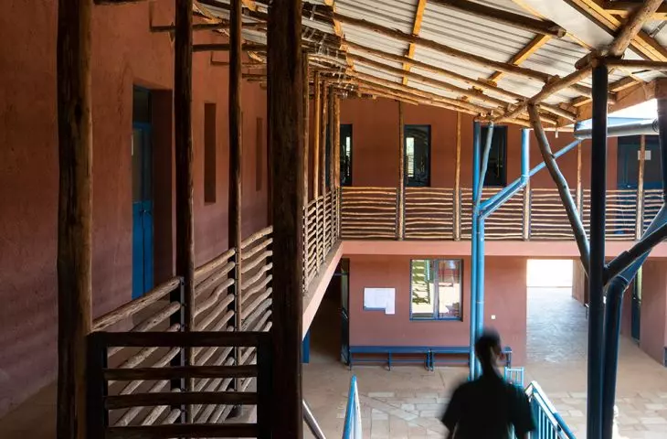 Interior view of the building with wooden beams and metal railings, showing a person descending the stairs