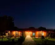 One-story, Busajo Campus building at night with wooden architectural elements against the starry sky
