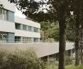 Two-storey modern building with a terrace, located among trees and greenery