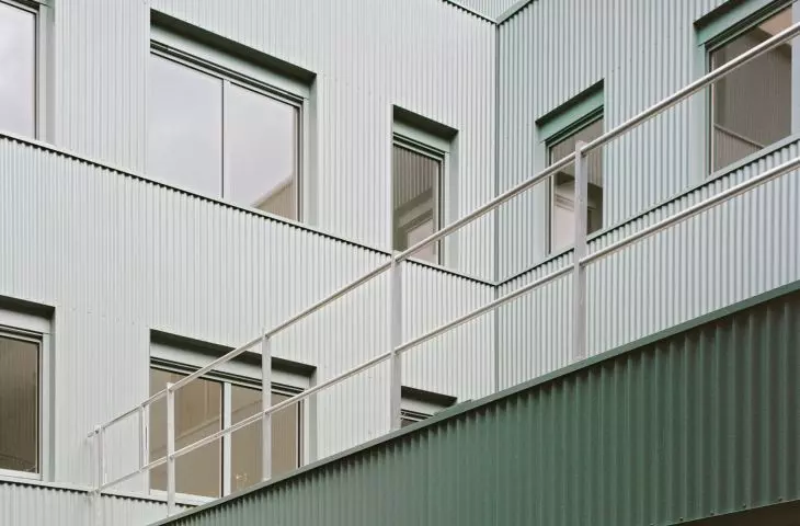 Modern greenish-colored five-story building with rectangular windows