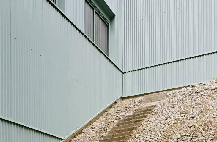 Concrete staircase next to the building with light green cladding and rectangular windows