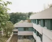 Modern building with green and beige facade surrounded by trees