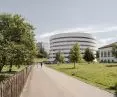 White, multi-story, cylindrical building, surrounded by trees and grassy areas