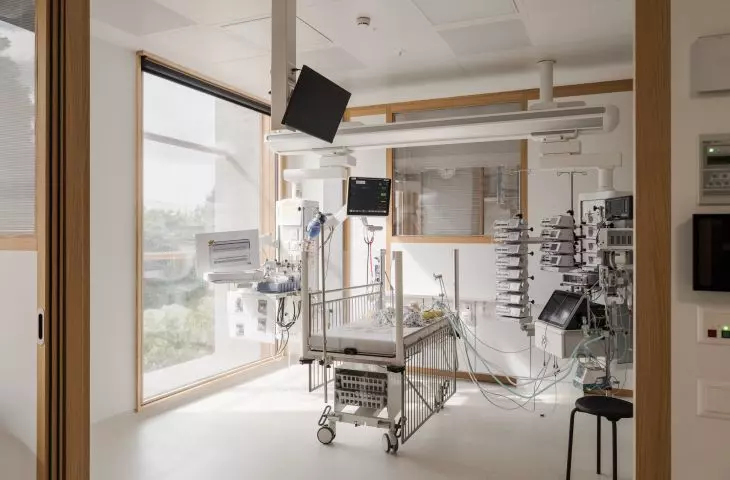 Hospital room with metal crib surrounded by medical equipment and monitors