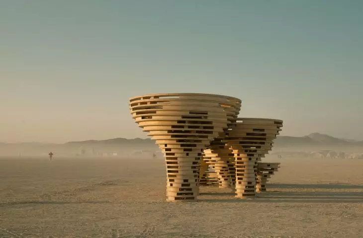 Mushroom-shaped wooden structures in the desert against a backdrop of mountains in Nevada