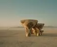 Mushroom-shaped wooden structures in the desert against a backdrop of mountains in Nevada