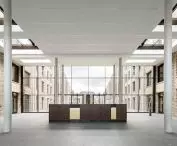 Spacious, modern interior with central reception area, brick walls, large windows and skylights