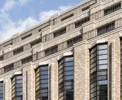Multi-storey beige building facade, large windows and metal railings