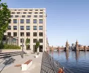 Modern bright building on the river with historic bridge in the background