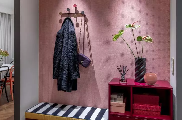 The alcove in the hall was furnished with a fuchsia dresser with a seat