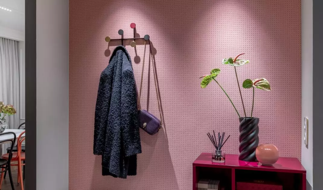 The alcove in the hall was furnished with a fuchsia dresser with a seat