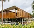 Modern house finished with wooden slats, surrounded by lush green plants