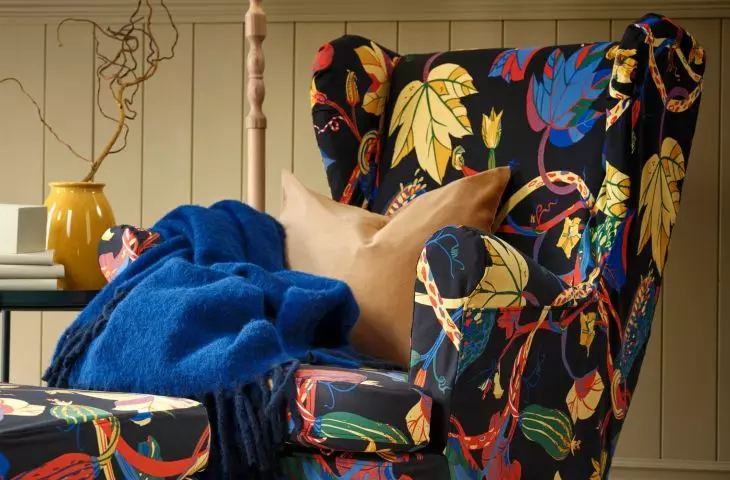 An earlobe armchair with a cover in a pattern of multicolored autumn leaves is the perfect choice for long evenings with a book